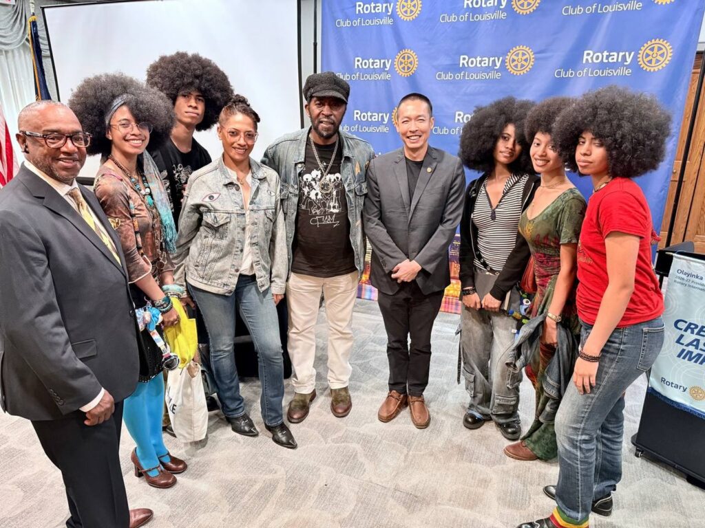 Di Tran stands with Dr. Kevin Fields and the Curtis Family C-Notes in front of a Rotary Club of Louisville backdrop on August 20, 2026.
