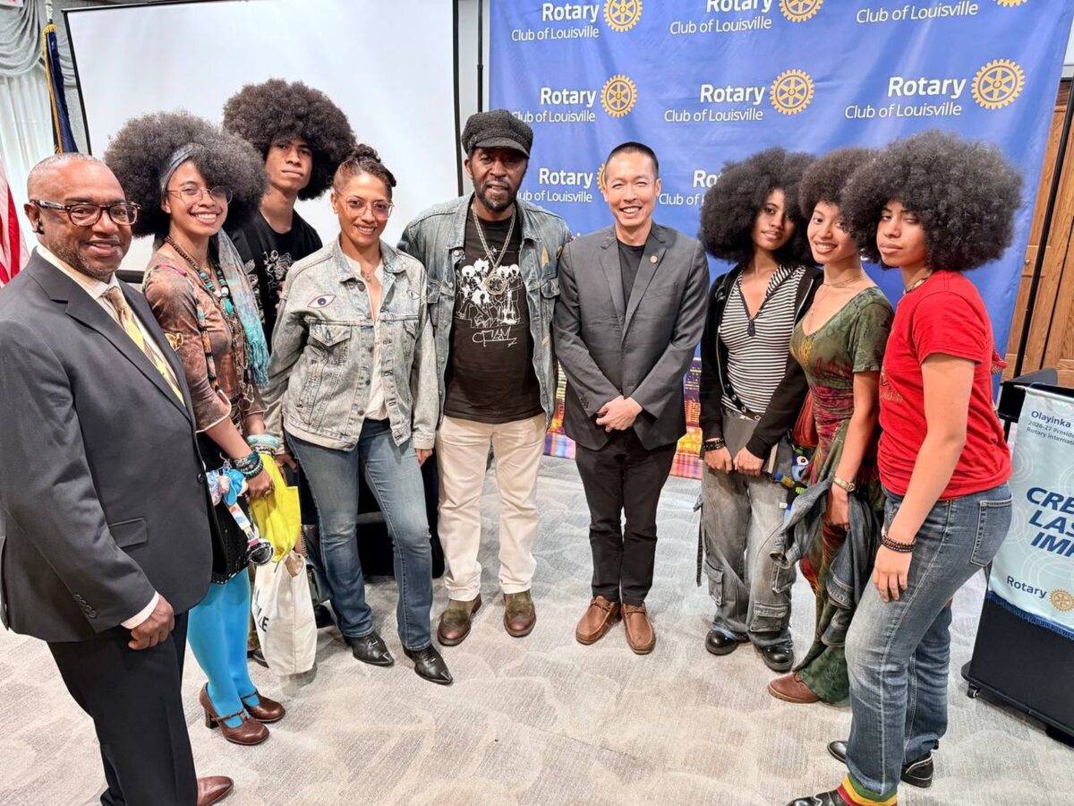 Di Tran stands with Dr. Kevin Fields and the Curtis Family C-Notes in front of a Rotary Club of Louisville backdrop on August 20, 2026.